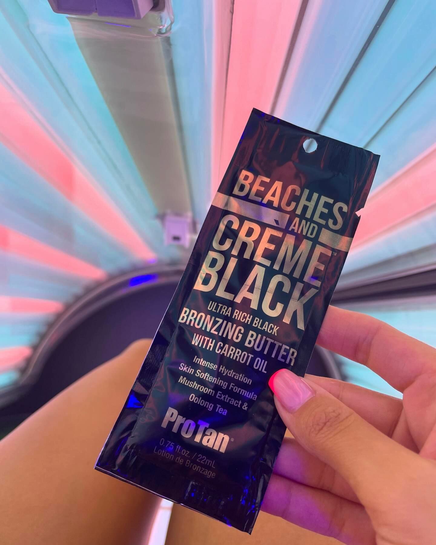 A sachet of Pro Tan Beaches and Creme Black held up in front of a lit sunbed